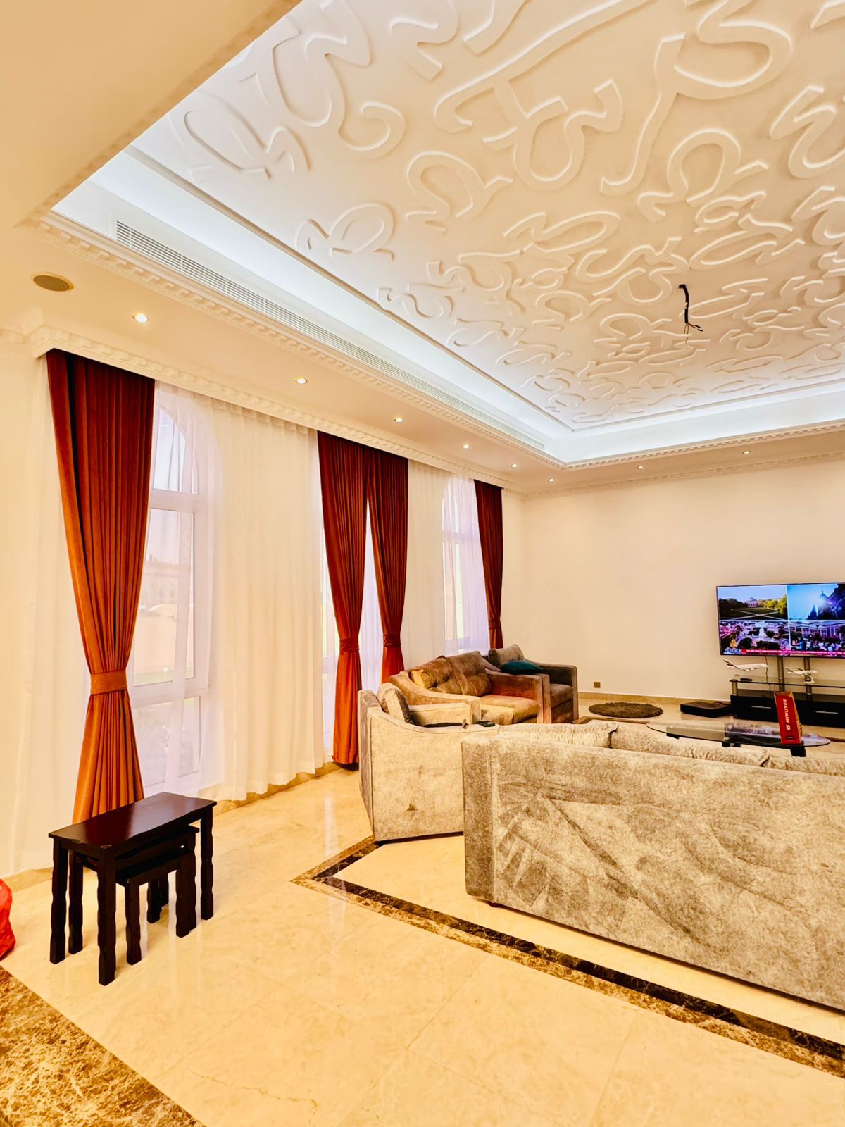 Floor-to-ceiling wave-fold curtains in a contemporary UAE living room